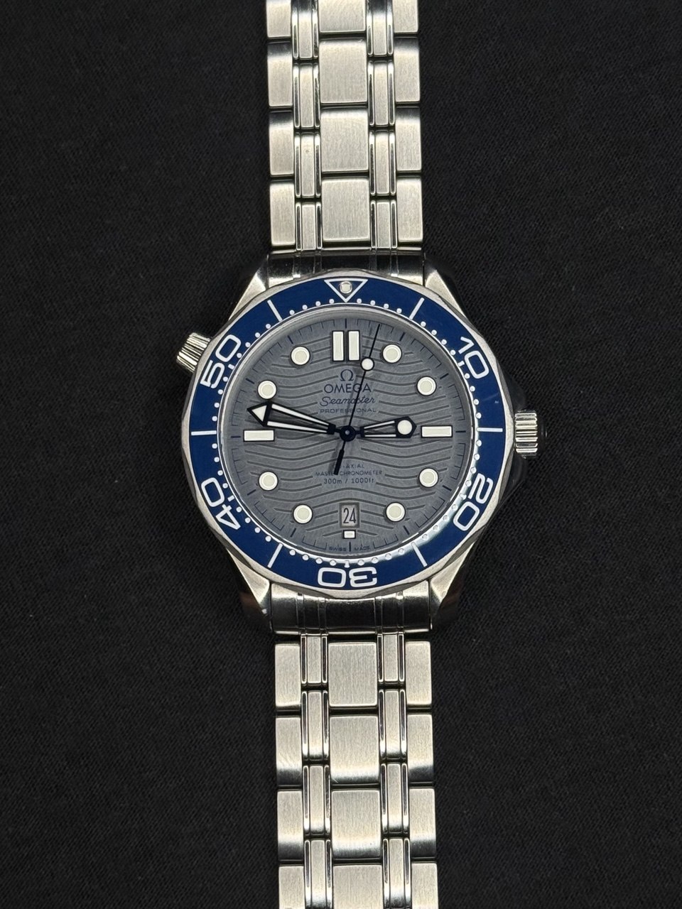 Omega Seamaster completo en flat lay sobre pared Santorini